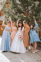 Group portrait of the bride and bridesmaids. A bride in a wedding dress and bridesmaids in beautiful dresses hold the bride's bouquet on the wedding day. photo