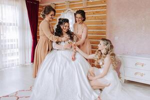 Friends rejoice with the bride in the morning. They take pictures, smile, help the bride fasten her dress. photo