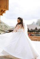 Rizado novia giros en su Boda vestido. magnífico vestir con largo mangas, abierto busto. verano Boda foto