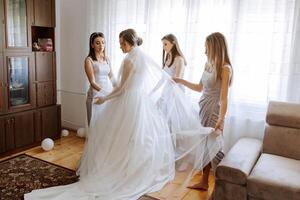 Friends rejoice with the bride in the morning. They take pictures, smile, help the bride fasten her dress. photo