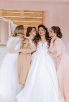 Friends rejoice with the bride in the morning. They take pictures, smile, help the bride fasten her dress. photo