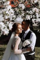 Wedding. Love and couple in garden for wedding. Celebration of ceremony and commitment. Save the date. Trust. The bride and groom embrace. The groom embraces the bride under a spring flowering tree. photo