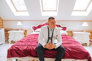 A stylish portrait of the groom preparing for the wedding ceremony in the morning. Groom's morning. Preparation for the groom's morning. The groom puts on a jacket. The confident look of a mature man. photo