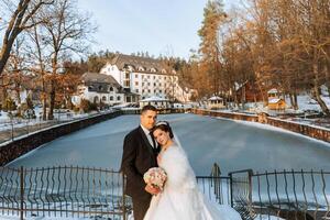 invierno boda. contento Pareja caminando en Boda ropa abrazando y sonriente en un invierno parque cubierto con nieve en su Boda día. invierno amor historia de un hermosa Pareja en Nevado invierno clima foto