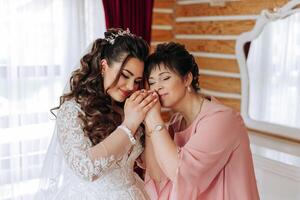 A beautiful and happy mother and her daughter, the bride, are standing next to each other. The best day for parents. Tender moments at the wedding. photo