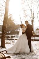 invierno boda. un contento Pareja en Boda ropa son abrazando y sonriente en un invierno parque cubierto con nieve en su Boda día. invierno amor historia de un hermosa Pareja en Nevado invierno clima foto