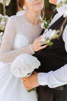 Wedding. Love and couple in garden for wedding. Celebration of ceremony and commitment. Save the date. Trust. The bride and groom embrace. The groom embraces the bride under a spring flowering tree. photo