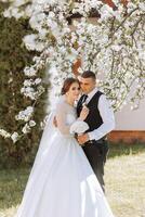Wedding. Love and couple in garden for wedding. Celebration of ceremony and commitment. Save the date. Trust. The bride and groom embrace. The groom embraces the bride under a spring flowering tree. photo
