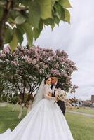 boda. amor y Pareja en jardín para boda. celebrando el ceremonia y compromiso. salvar el fecha. confianza. el novia y novio abrazo en contra el antecedentes de un primavera floreciente árbol. foto