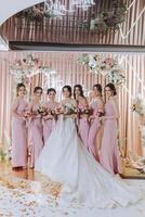 grupo retrato de el novia y damas de honor novia en un Boda vestir y damas de honor en rosado o polvo vestidos y participación elegante ramos de flores en el Boda día. foto