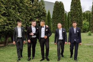 Cheerful, young, energetic witnesses of the groom next to the groom. Friends congratulate the groom. Groom and his funny friends having fun on the wedding day of the newlyweds. photo