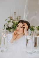 A beautiful brunette bride with a tiara in her hair is getting ready for the wedding in a beautiful robe in boudoir style. Close-up wedding portrait, photo. photo