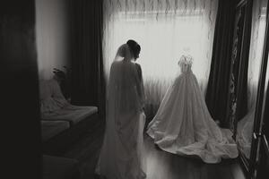 A happy bride is preparing for her luxurious wedding in a hotel room, with a wedding dress on a mannequin nearby. Portrait of a woman with fashionable hair, makeup and a smile in a dressing gown. photo