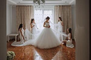 Friends rejoice with the bride in the morning. They take pictures, smile, help the bride fasten her dress. photo