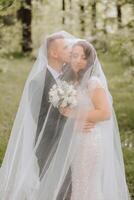 Wedding. Love and couple in garden for wedding. Celebration of ceremony and commitment. Save the date. Trust. The bride and groom embrace. The groom embraces the bride under the veil. photo