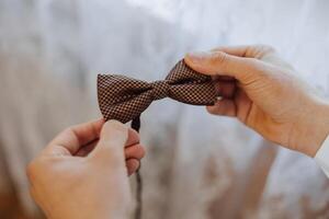 man's tie in hands, close-up photo of hands. The groom is preparing for the ceremony. Last preparations.