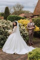 A beautiful young bride, in a summer park, walks ahead of her groom. Beautiful wedding white dress. Walks in the park. A happy and loving couple. photo