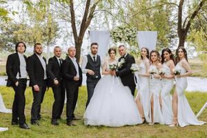 full-length portrait of the newlyweds and their friends at the wedding. The bride and groom with bridesmaids and friends of the groom are having fun and rejoicing at the wedding. photo