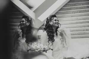 portrait of a luxurious bride in boudoir style near a mirror with reflection. Preparing the bride for the wedding in the morning in a white robe. photo