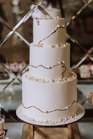 A large luxurious multi-tiered wedding cake is decorated with white pearls in the banquet hall. Wedding dessert under the evening light. Wedding decor. photo