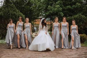 grupo retrato de el novia y damas de honor un novia en un Boda vestir y damas de honor en plata vestidos sostener elegante ramos de flores en su Boda día. foto