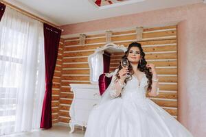 A wonderful beautiful portrait of a young bride. Beautiful bride with wedding makeup and jewelry wreath on long curly hair. Wedding photo model with brown eyes in a beautiful interior.