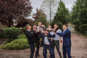 Cheerful, young, energetic witnesses of the groom next to the groom. Friends congratulate the groom. Groom and his funny friends having fun on the wedding day of the newlyweds. photo