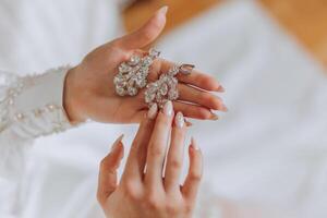 de cerca de un hermosa niña en suave satín ropa interior vistiendo pendientes. Boda Mañana de el novia. publicidad decoraciones un mujer va en un fecha. foto