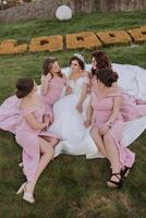 grupo retrato de el novia y damas de honor novia en un Boda vestir y damas de honor en rosado o polvo vestidos y participación elegante ramos de flores en el Boda día. foto