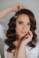 A beautiful brunette bride with a tiara in her hair is getting ready for the wedding in a beautiful robe in boudoir style. Close-up wedding portrait, photo. photo