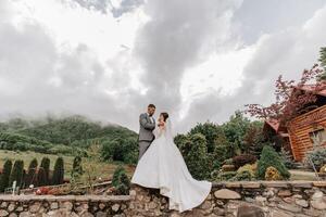 Wedding. Love and couple in garden for wedding. Celebration of ceremony and commitment. Save the date. Trust. The groom embraces the bride against the background of mountains and a cloudy sky. photo