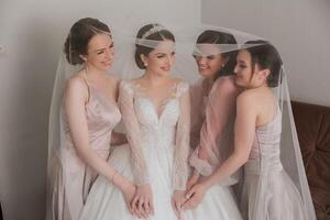 Friends rejoice with the bride in the morning. They take pictures, smile, help the bride fasten her dress. photo