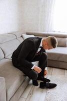 A man's hands tie the laces of his new shoes. People, business, fashion and footwear concept - close-up of a man's legs and hands tying shoelaces. The groom puts on his shoes. photo