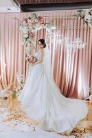 a brunette bride in a tiara poses with a bouquet of white and pink flowers. Beautiful hair and makeup. Spring wedding photo