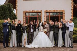 full-length portrait of the newlyweds and their friends at the wedding. The bride and groom with bridesmaids and friends of the groom are having fun and rejoicing at the wedding. photo