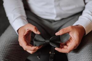 man's tie in hands, close-up photo of hands. The groom is preparing for the ceremony. Last preparations.