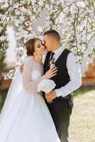 Wedding. Love and couple in garden for wedding. Celebration of ceremony and commitment. Save the date. Trust. The bride and groom embrace. The groom embraces the bride under a spring flowering tree. photo