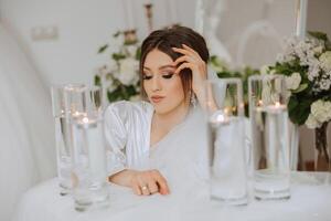 A beautiful brunette bride with a tiara in her hair is getting ready for the wedding in a beautiful robe in boudoir style. Close-up wedding portrait, photo. photo