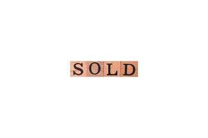 The inscription Sold made of wooden cubes on a plain background photo