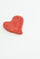 Red heart shaped ceramic piece with white background photo