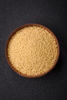 Wheat porridge couscous grains on a dark concrete background photo