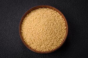 Wheat porridge couscous grains on a dark concrete background photo