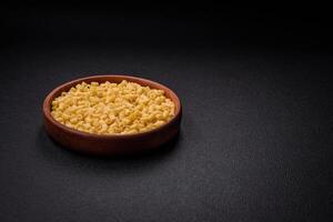 Raw ditali pasta made from durum wheat on a dark concrete background photo