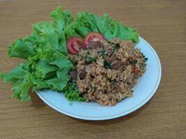 Delicious Indonesian fried rice nasi goreng with lots of lettuce, mustard greens and tomatoes served on a white plate photo