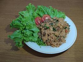 Delicious Indonesian fried rice nasi goreng with lots of lettuce, mustard greens and tomatoes served on a white plate photo