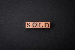 The inscription Sold made of wooden cubes on a plain background photo