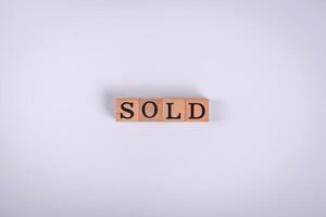 The inscription Sold made of wooden cubes on a plain background photo