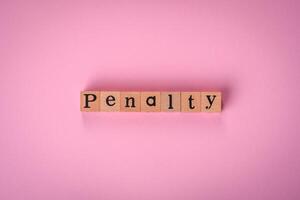 The inscription Penalty made up of wooden cubes on a plain background photo