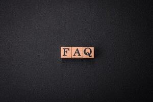 The inscription FAQ made up of wooden cubes on a plain background photo