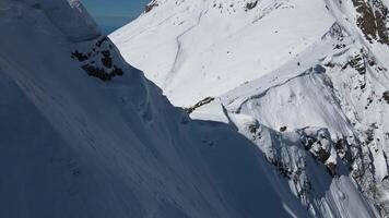 snöig berg med överhäng. snowboardåkare på en dela styrelse skidor längs de bergsrygg video